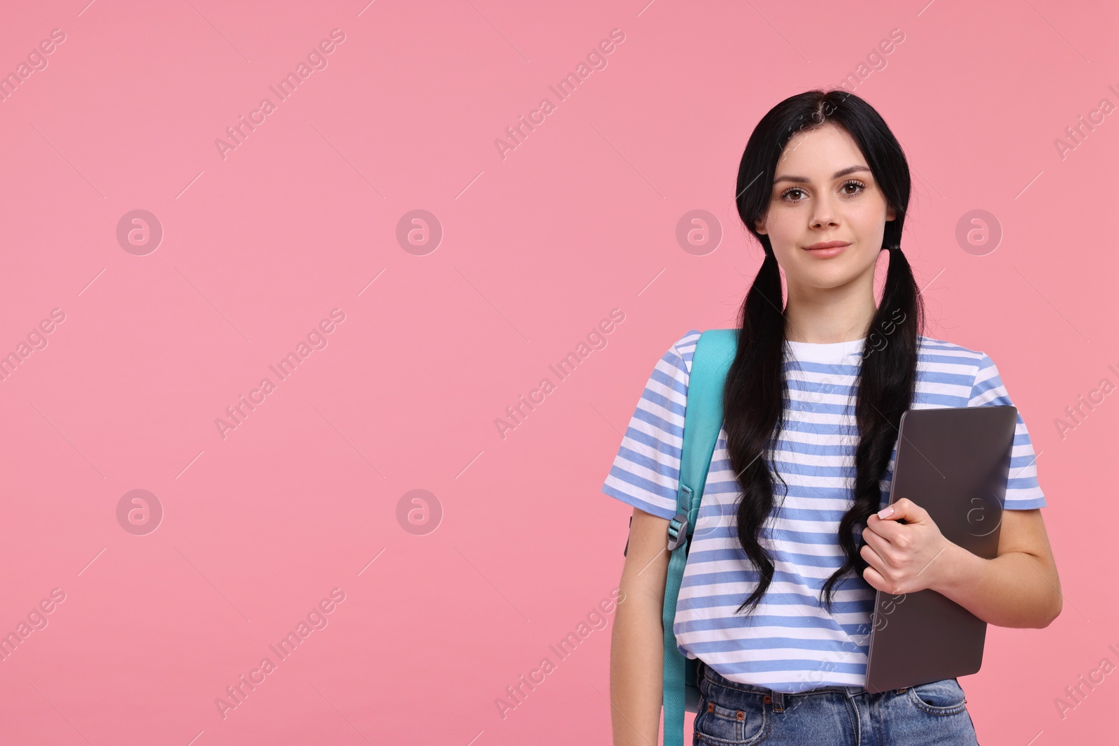 Photo of Student with laptop on pink background. Space for text
