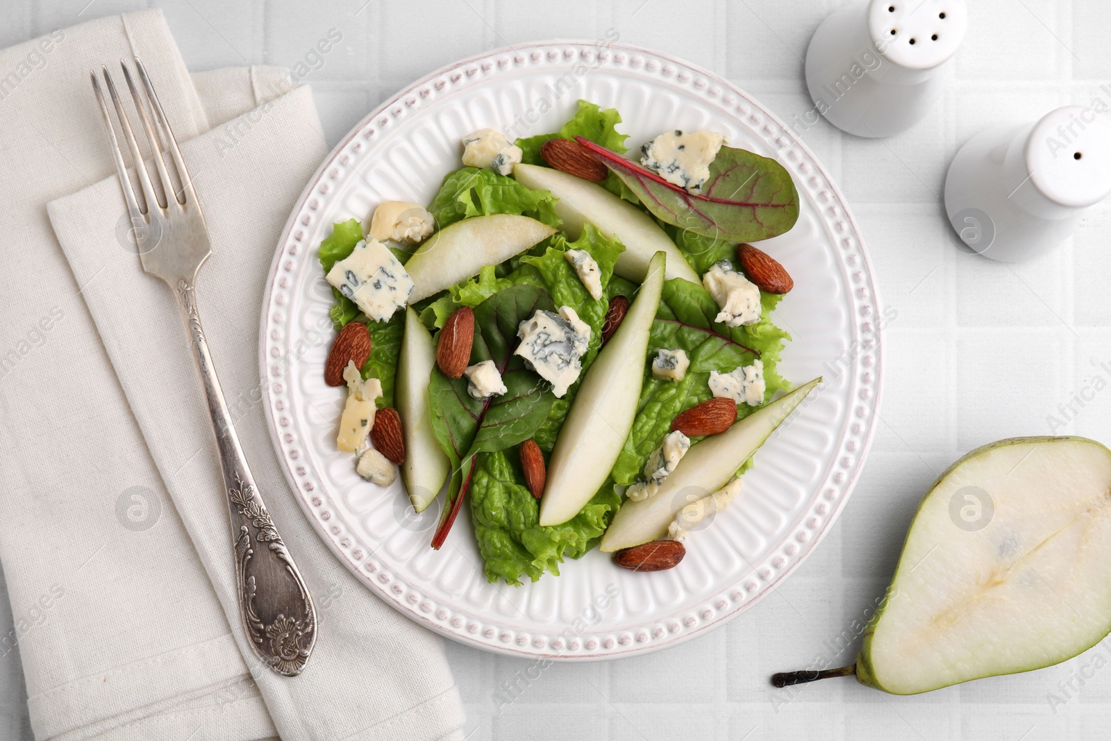 Photo of Delicious pear salad served on white tiled table, flat lay