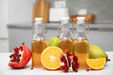 Photo of Homemade fermented kombucha and fresh fruits on white table in kitchen