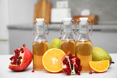 Homemade fermented kombucha and fresh fruits on white table in kitchen