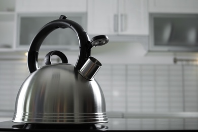 Photo of Modern kettle with whistle on stove in kitchen, space for text