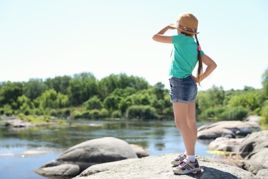 Photo of Little girl at riverside. Summer camp
