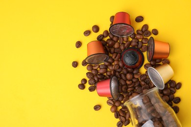 Photo of Many coffee capsules, beans and glass jar on yellow background, flat lay. Space for text