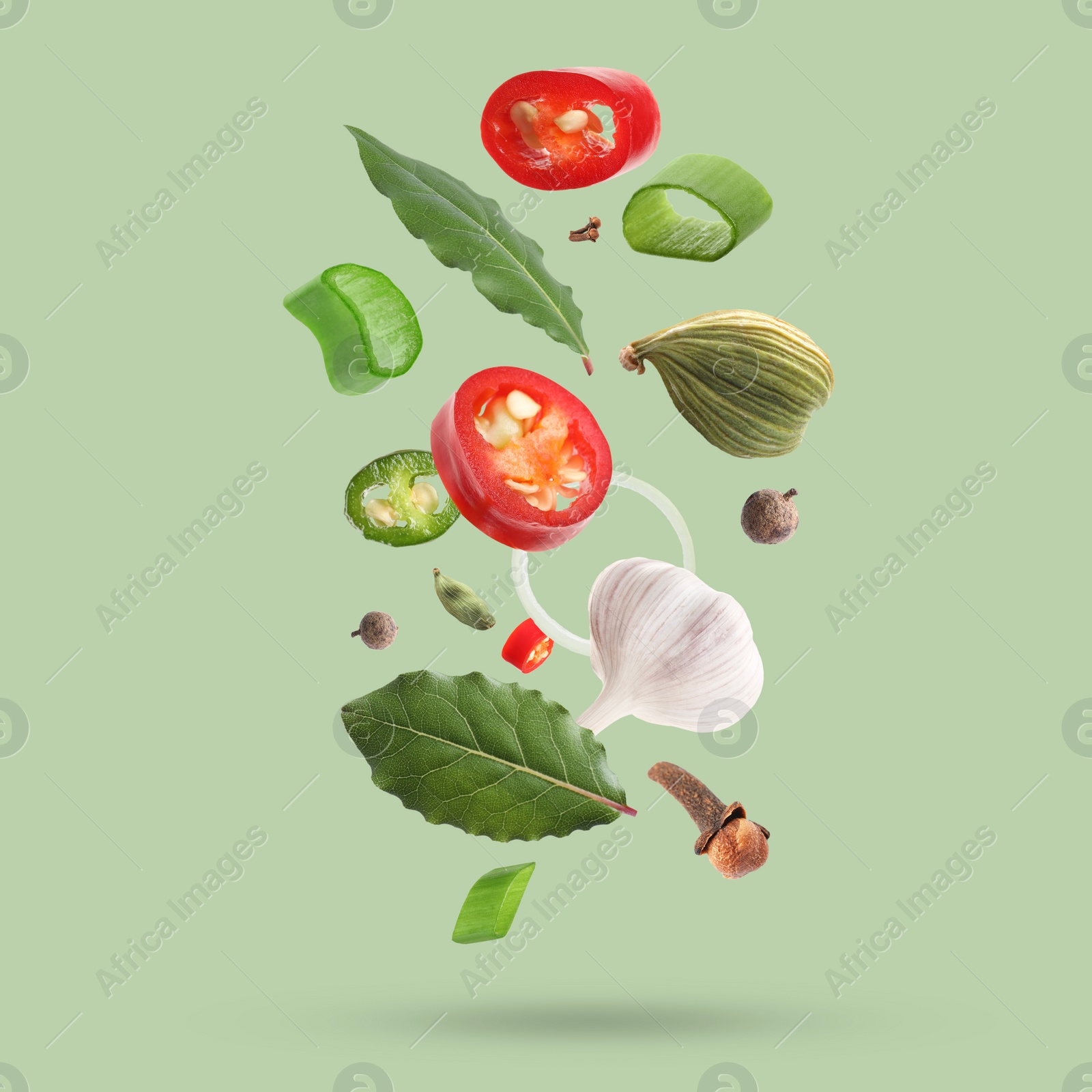 Image of Different spices falling on light green background