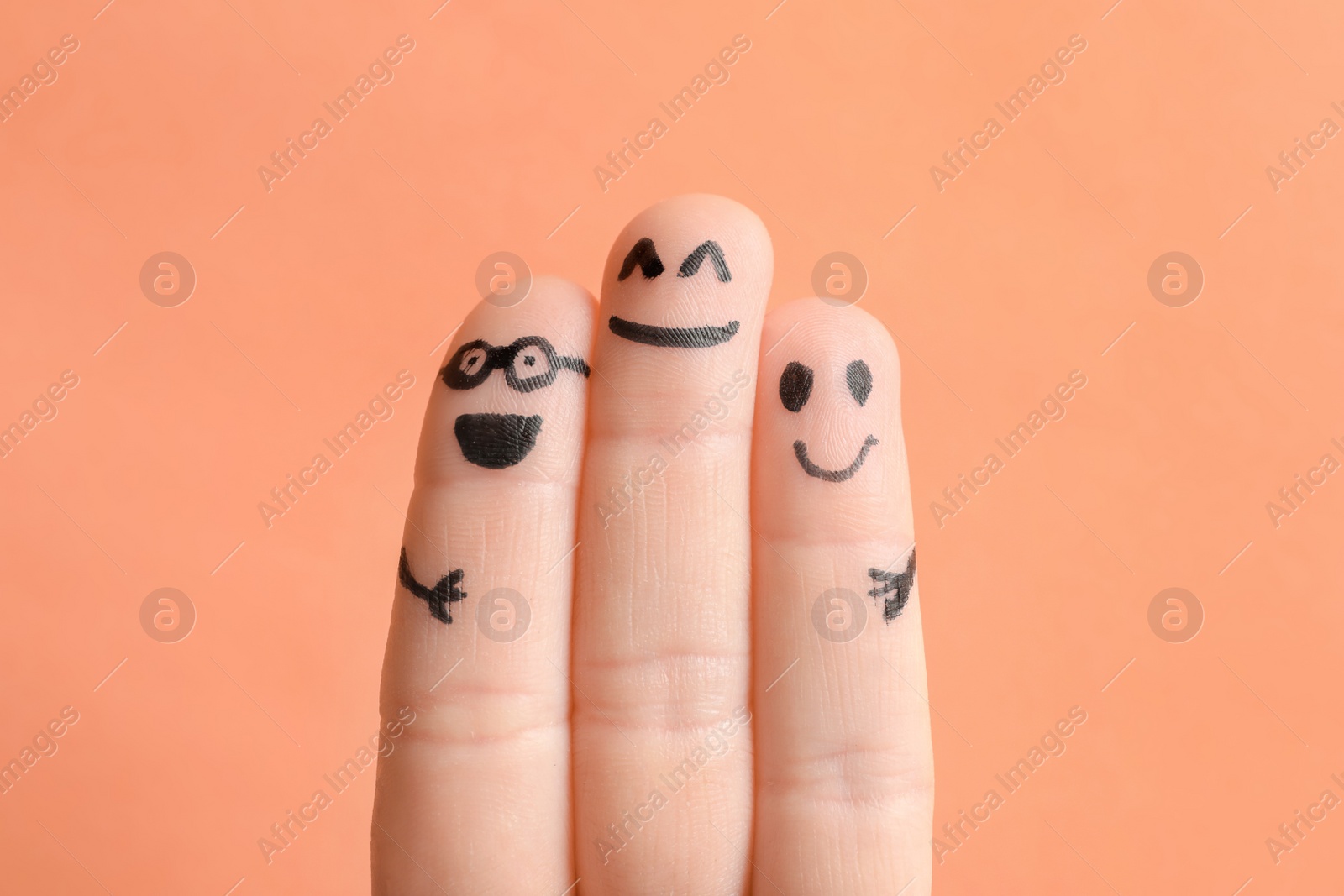 Photo of Fingers with drawings of happy faces against color background. Unity concept