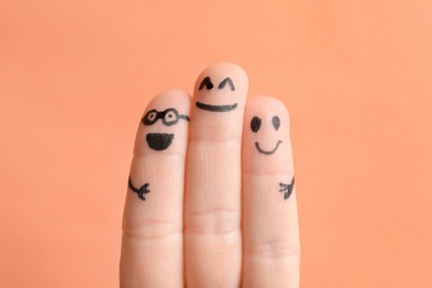 Photo of Fingers with drawings of happy faces against color background. Unity concept