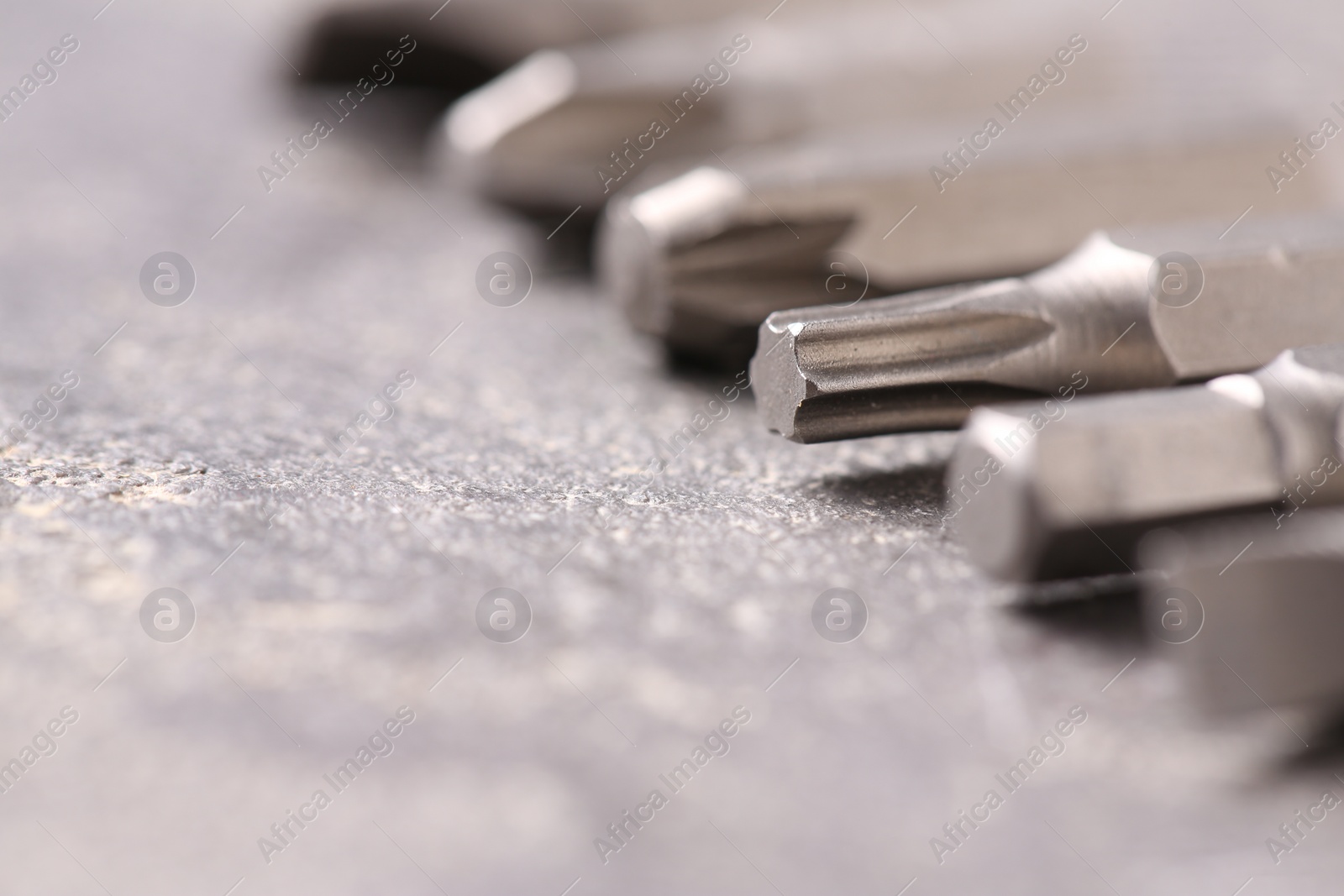 Photo of Different screwdriver bits on grey table, closeup