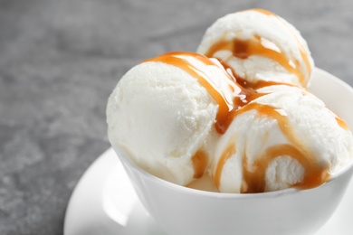 Tasty ice cream with caramel sauce in mug on table, closeup