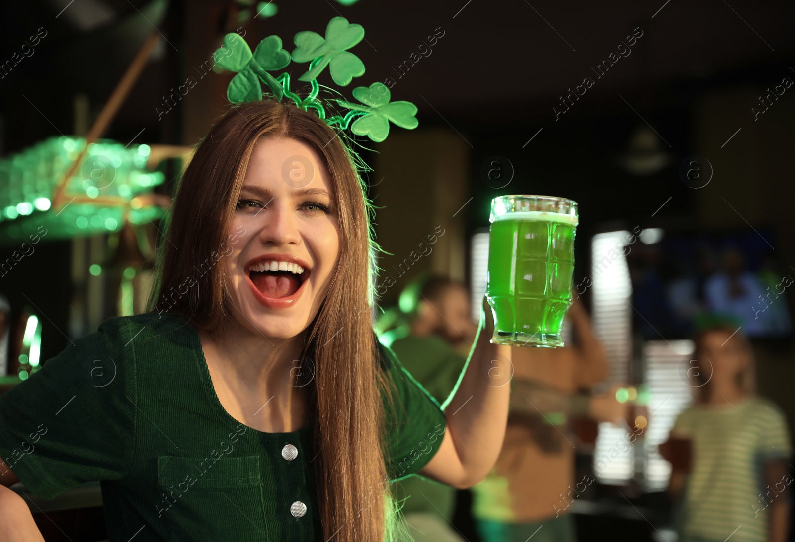 Photo of Young woman with glass of green beer in pub. St. Patrick's Day celebration