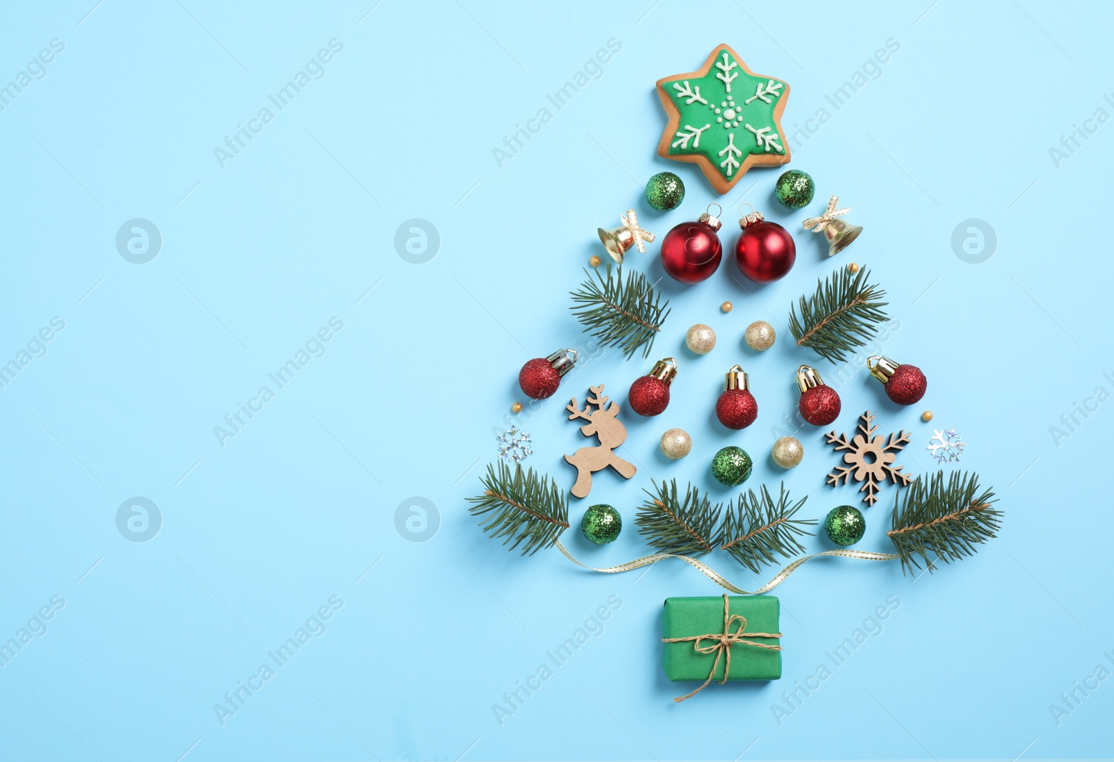 Photo of Christmas tree silhouette of fir branches and festive decoration on light blue background, flat lay. Space for text