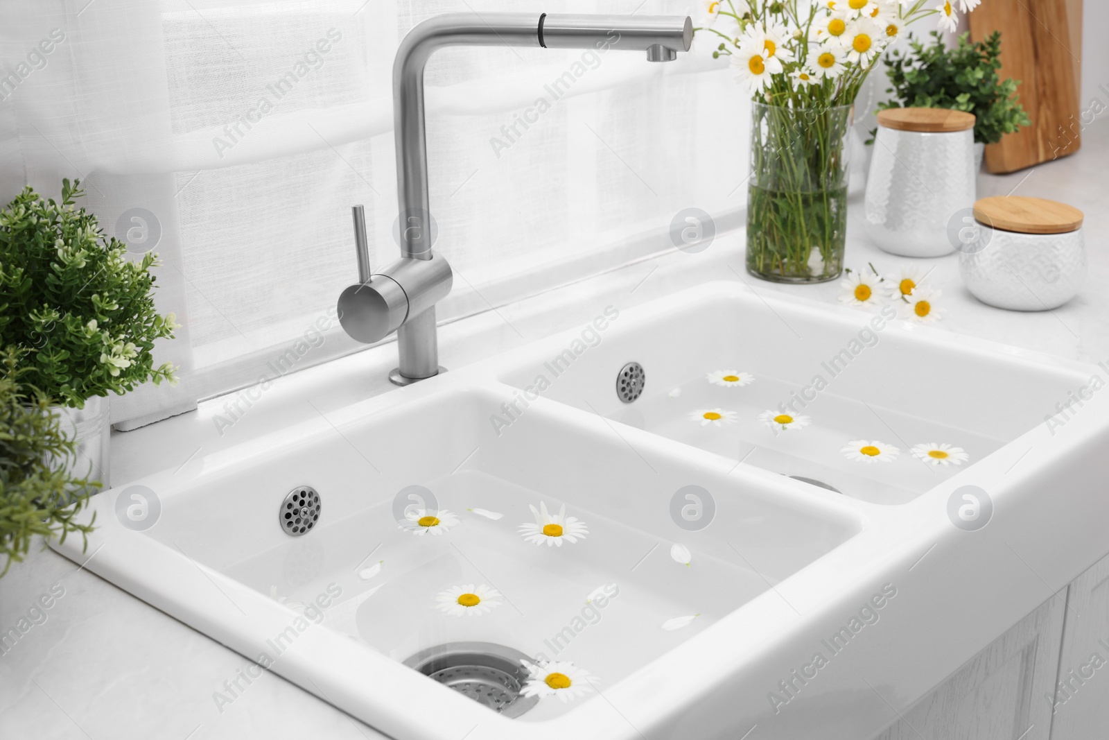 Photo of Sink with water and beautiful chamomiles indoors