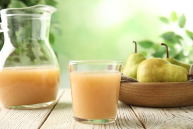 Fresh pear juice in glass on white wooden table, closeup