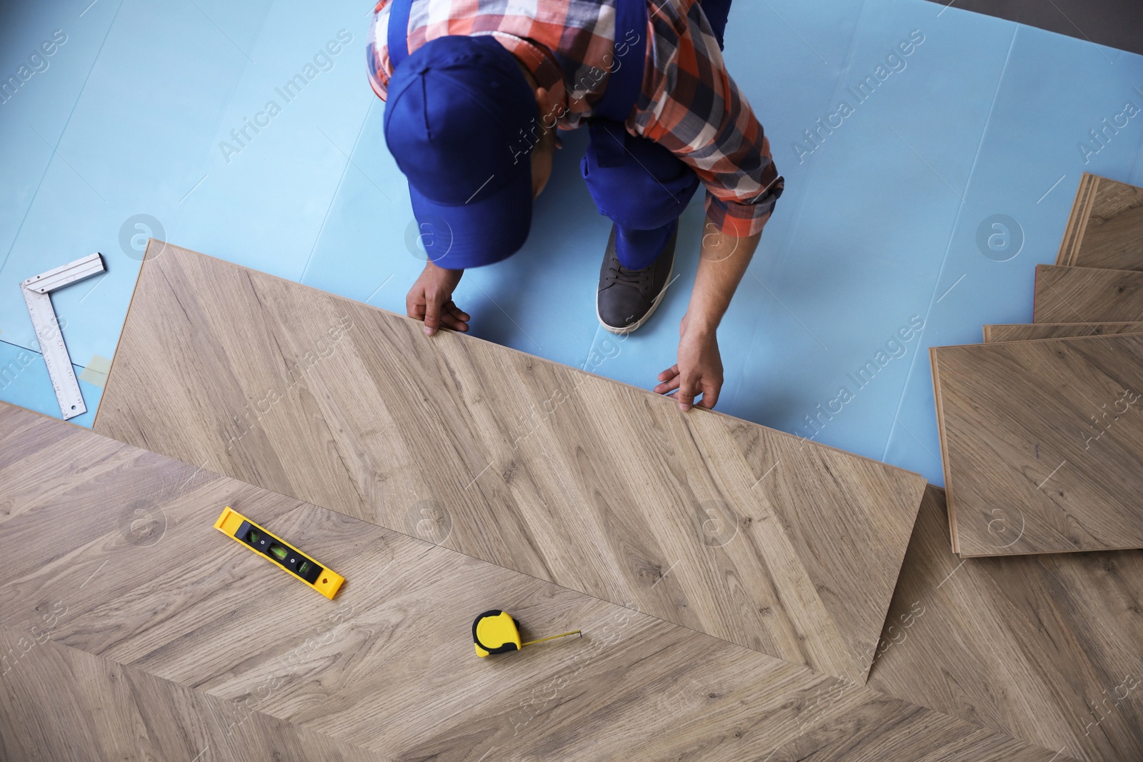 Photo of Worker installing laminated wooden floor indoors, above view
