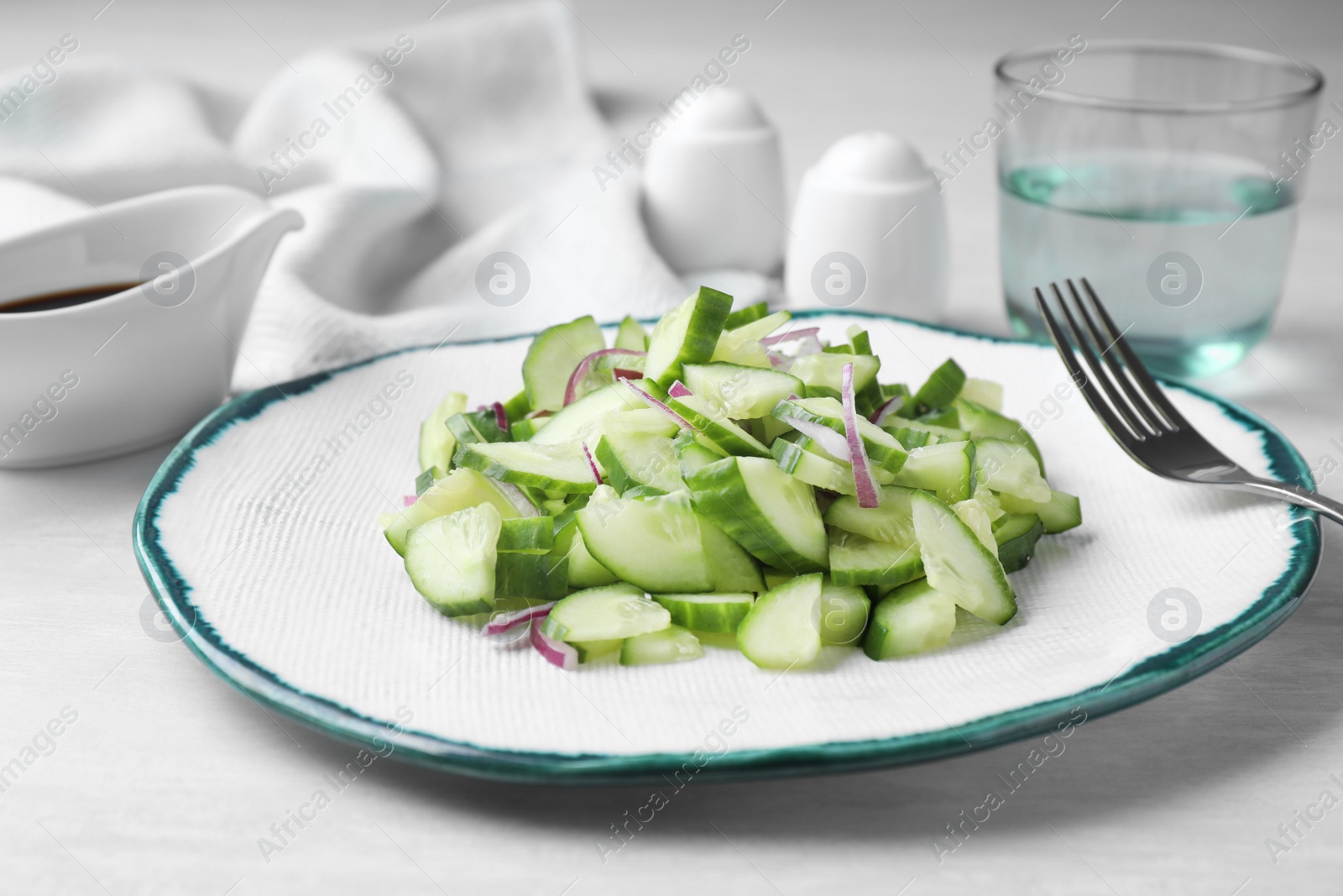 Photo of Plate of vegetarian salad with cucumber and onion served on table