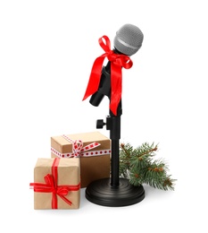 Microphone with red bow, gift boxes and festive decor on white background. Christmas music