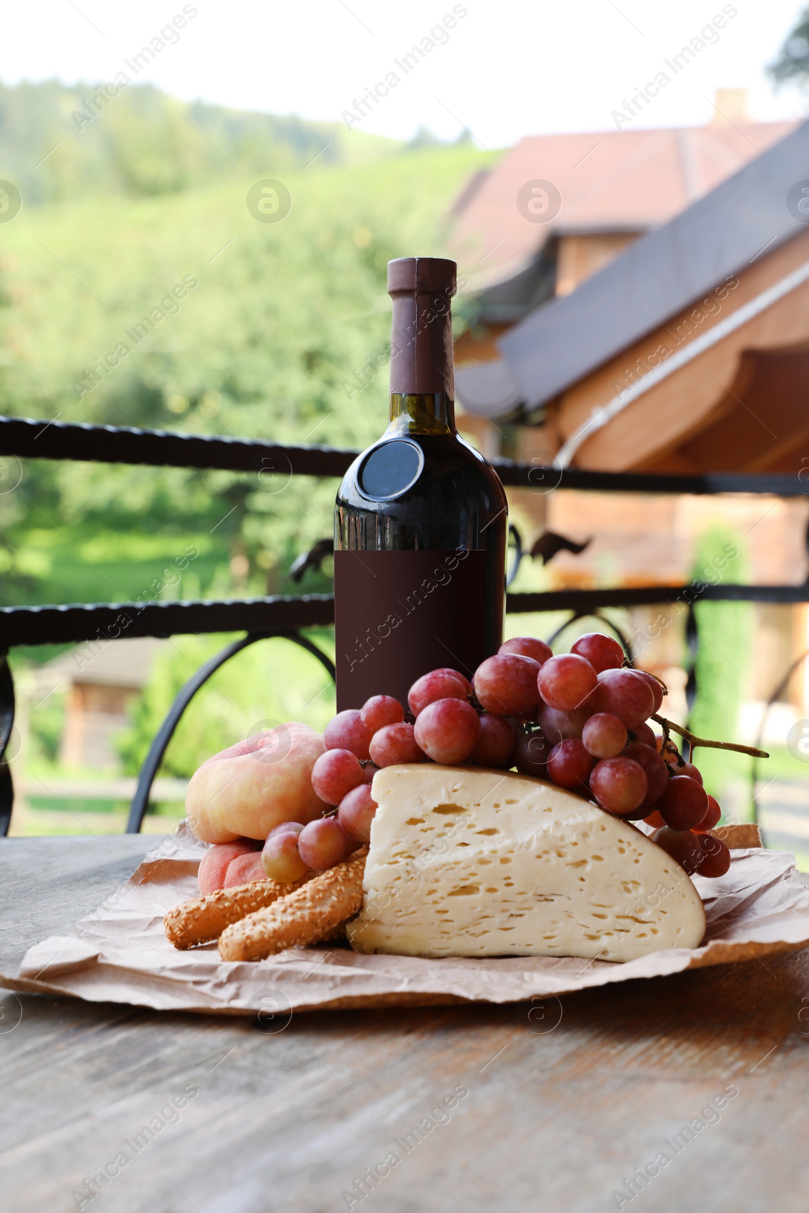 Photo of Bunch of grapes with wine in bottle, cheese and peaches on wooden table