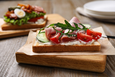 Photo of Tasty sandwich with ham served on wooden table