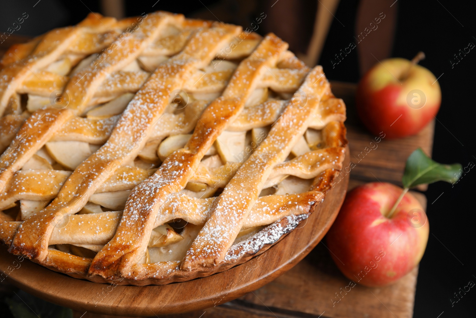 Photo of Delicious traditional apple pie on wooden stand, closeup