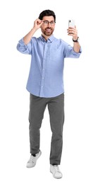 Smiling man taking selfie with smartphone on white background