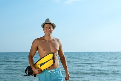 Happy man with flippers near sea on beach