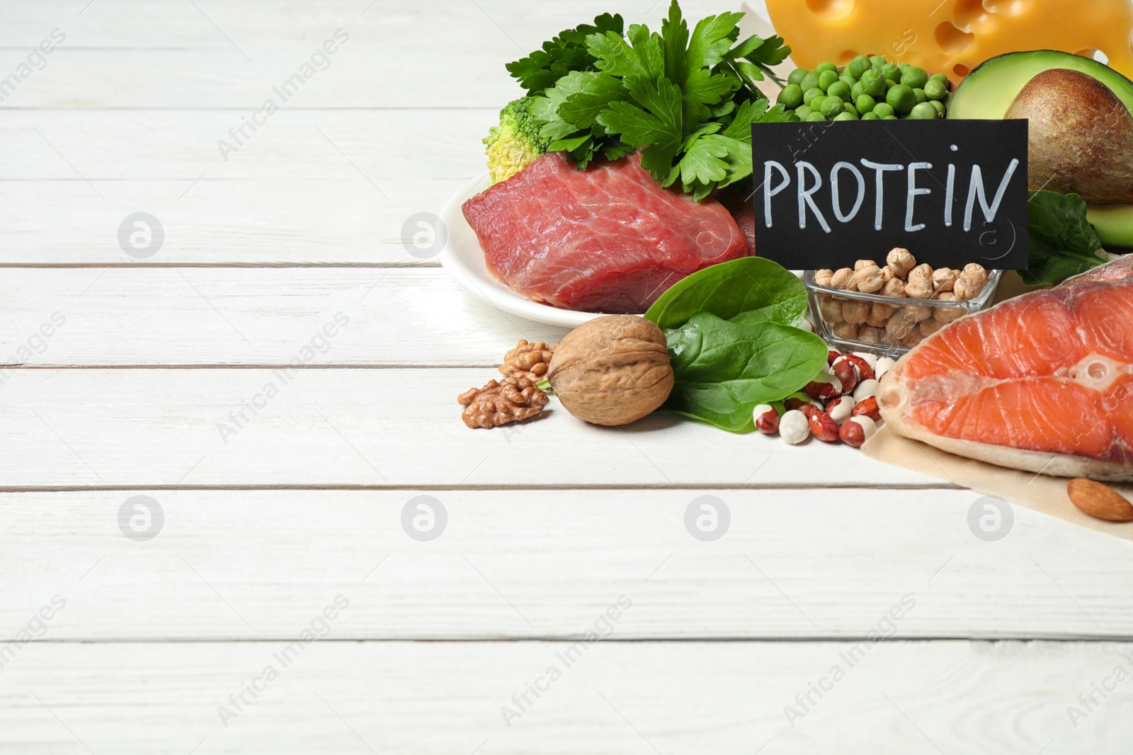 Photo of Card with word PROTEIN and different products on white wooden table. Space for text