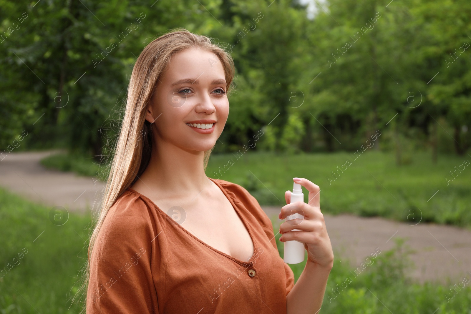 Photo of Woman using insect repellent in park. Tick bites prevention