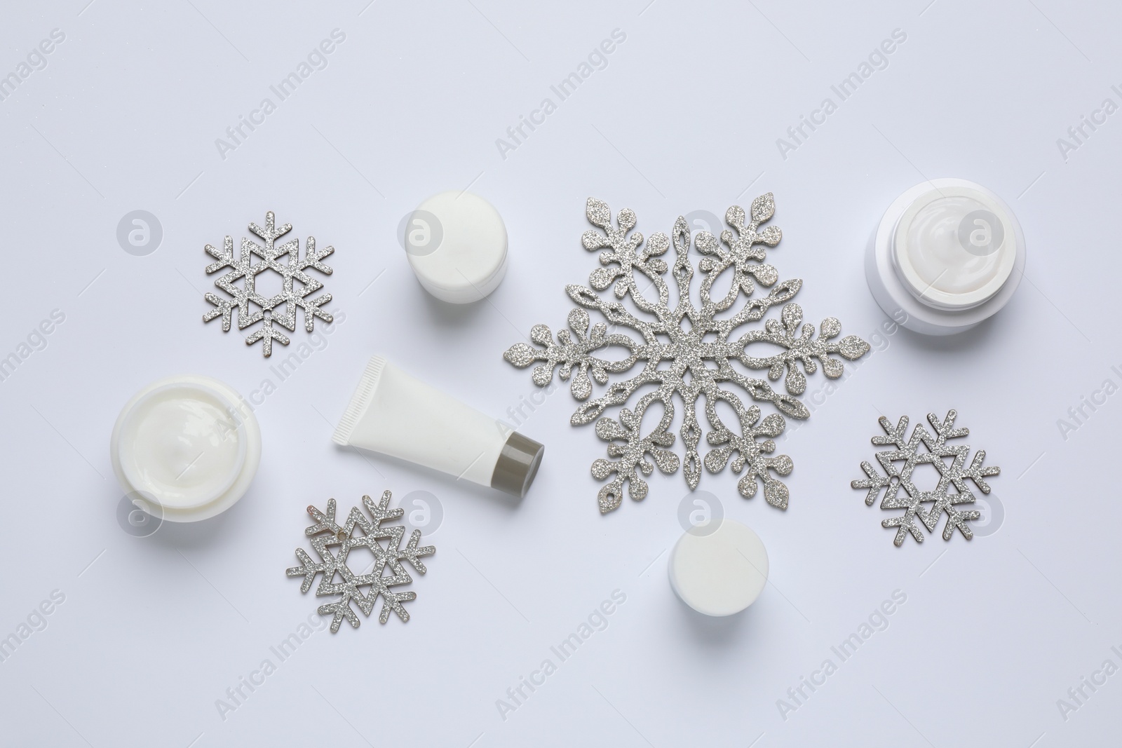 Photo of Composition with cosmetic products and snowflakes on white background, top view. Winter skin care