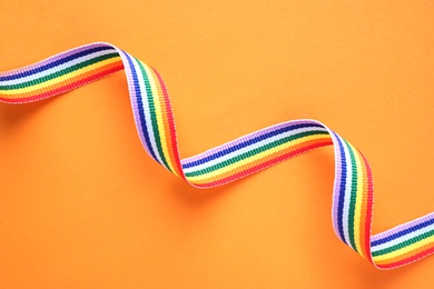 Bright rainbow ribbon on color background, top view. Symbol of gay community