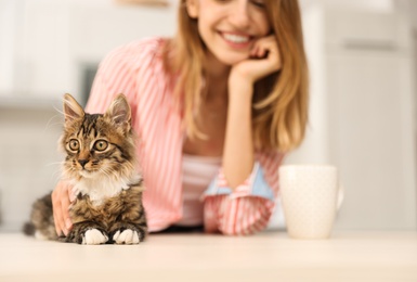 Photo of Young woman with cat at home, closeup. Owner and pet