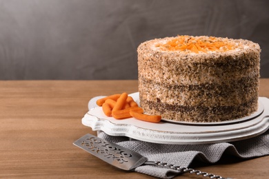 Sweet carrot cake with delicious cream on wooden table against color background. Space for text