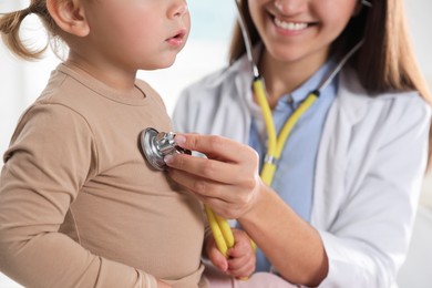 Pediatrician examining baby with stethoscope in clinic, closeup
