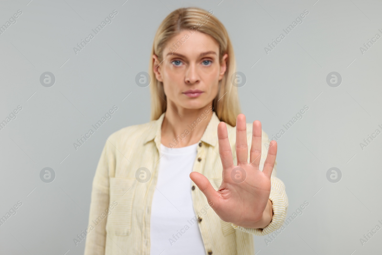 Photo of Woman showing stop gesture on grey background