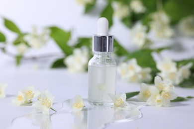 Photo of Essential oil in bottle and beautiful jasmine flowers on white background