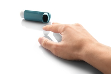 Photo of Woman reaching for asthma inhaler on white background