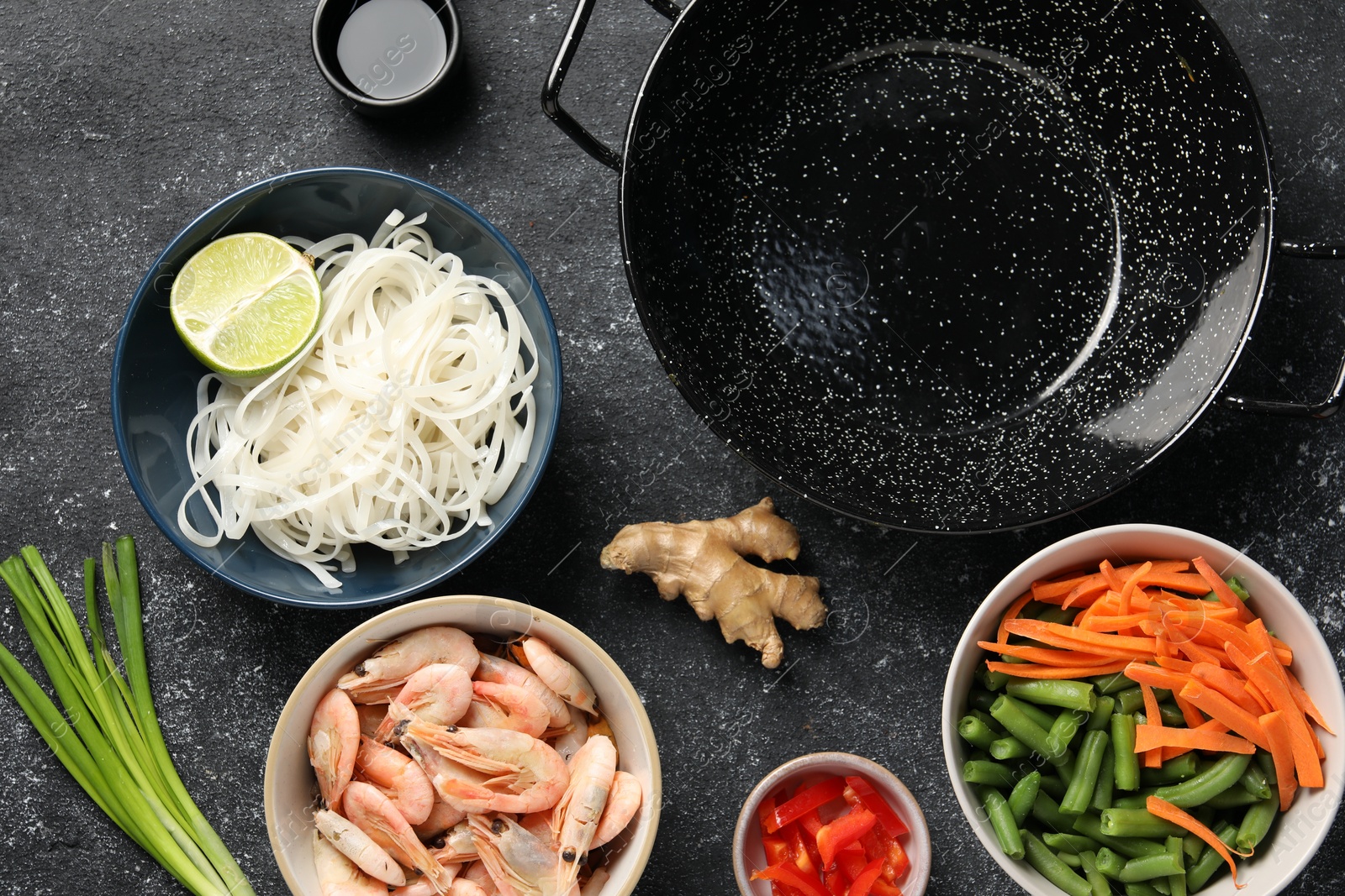 Photo of Flat lay composition with black wok and products on dark textured table