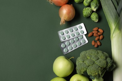 Photo of Pills and food on green background, flat lay with space for text. Prebiotic supplements