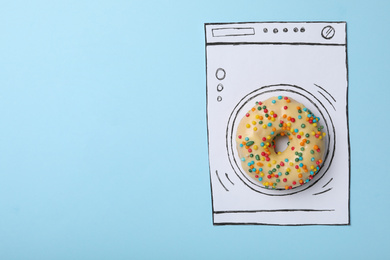 Washing machine made with donut and paper on light blue background, top view. Space for text