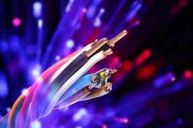 Image of Colorful electrical wires against dark background with blurred lights, closeup. Space for text