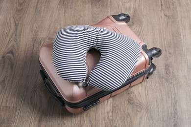 Photo of Striped travel pillow and suitcase on floor