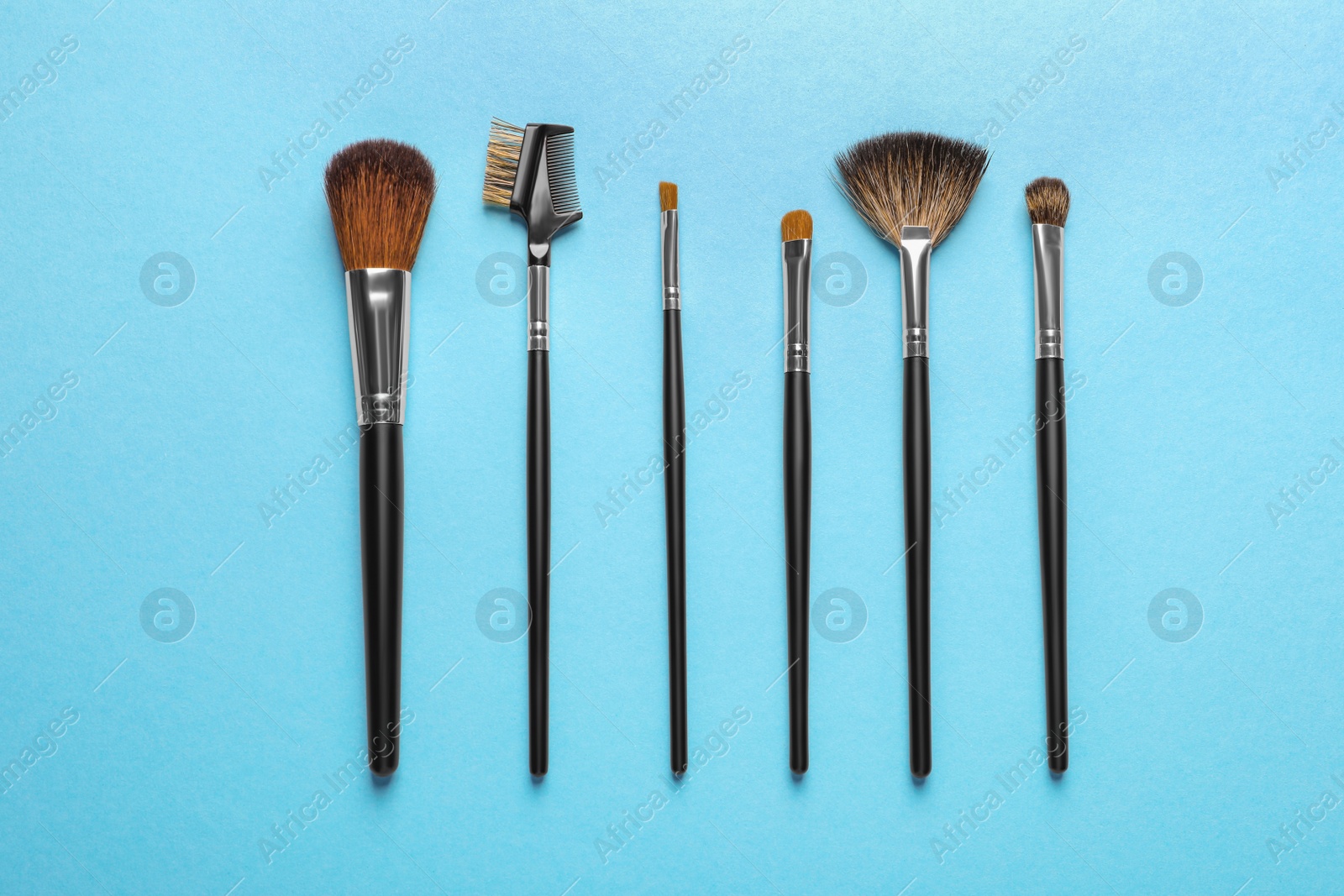 Photo of Set of makeup brushes on light blue background, flat lay