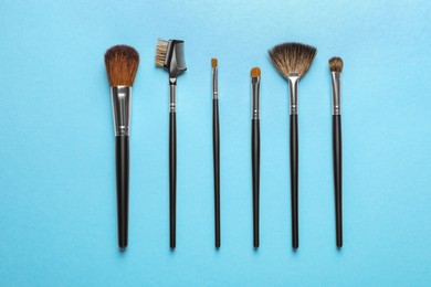 Photo of Set of makeup brushes on light blue background, flat lay