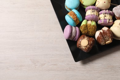 Photo of Delicious colorful macarons on light wooden table, top view. Space for text