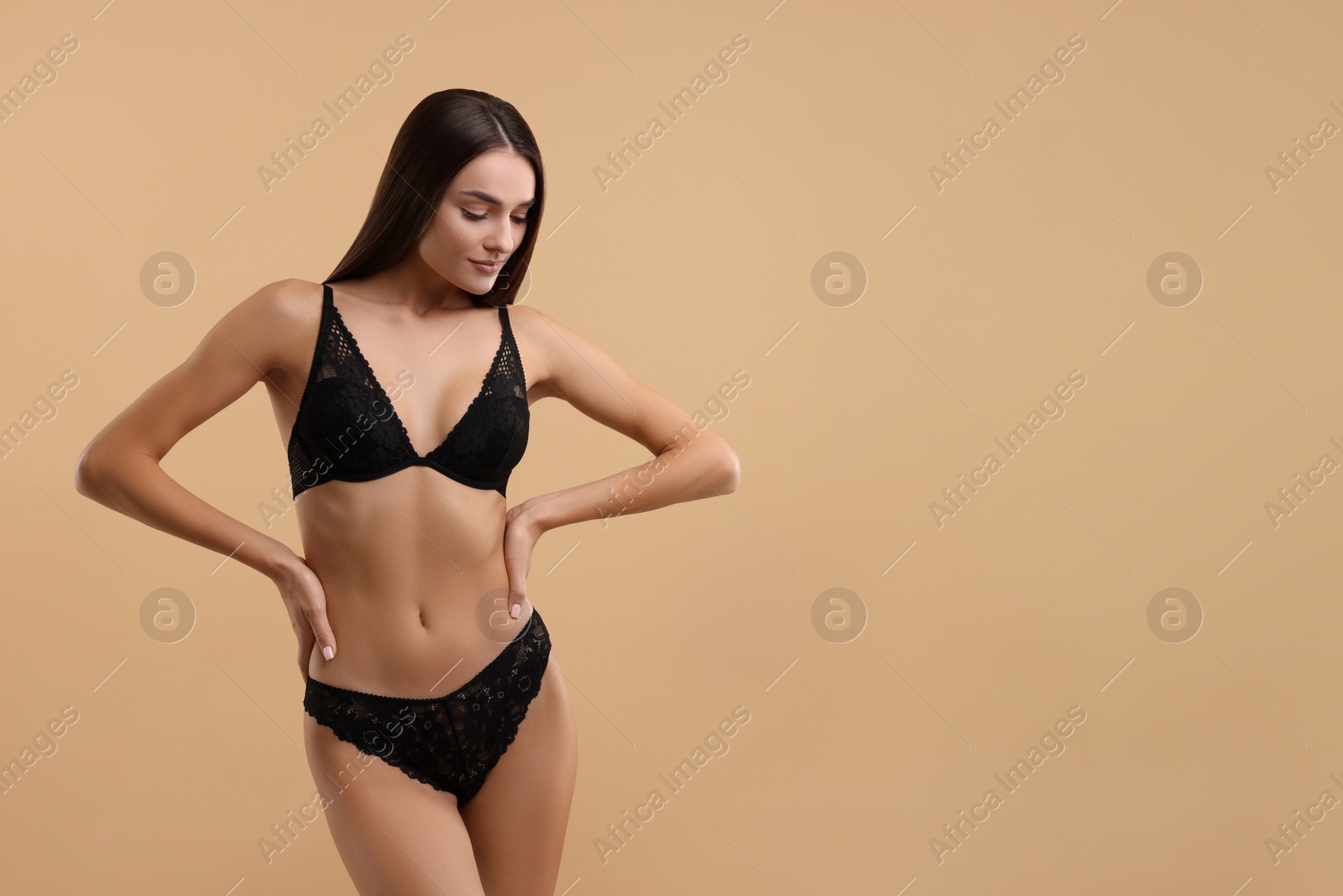 Photo of Young woman in elegant black underwear on beige background. Space for text