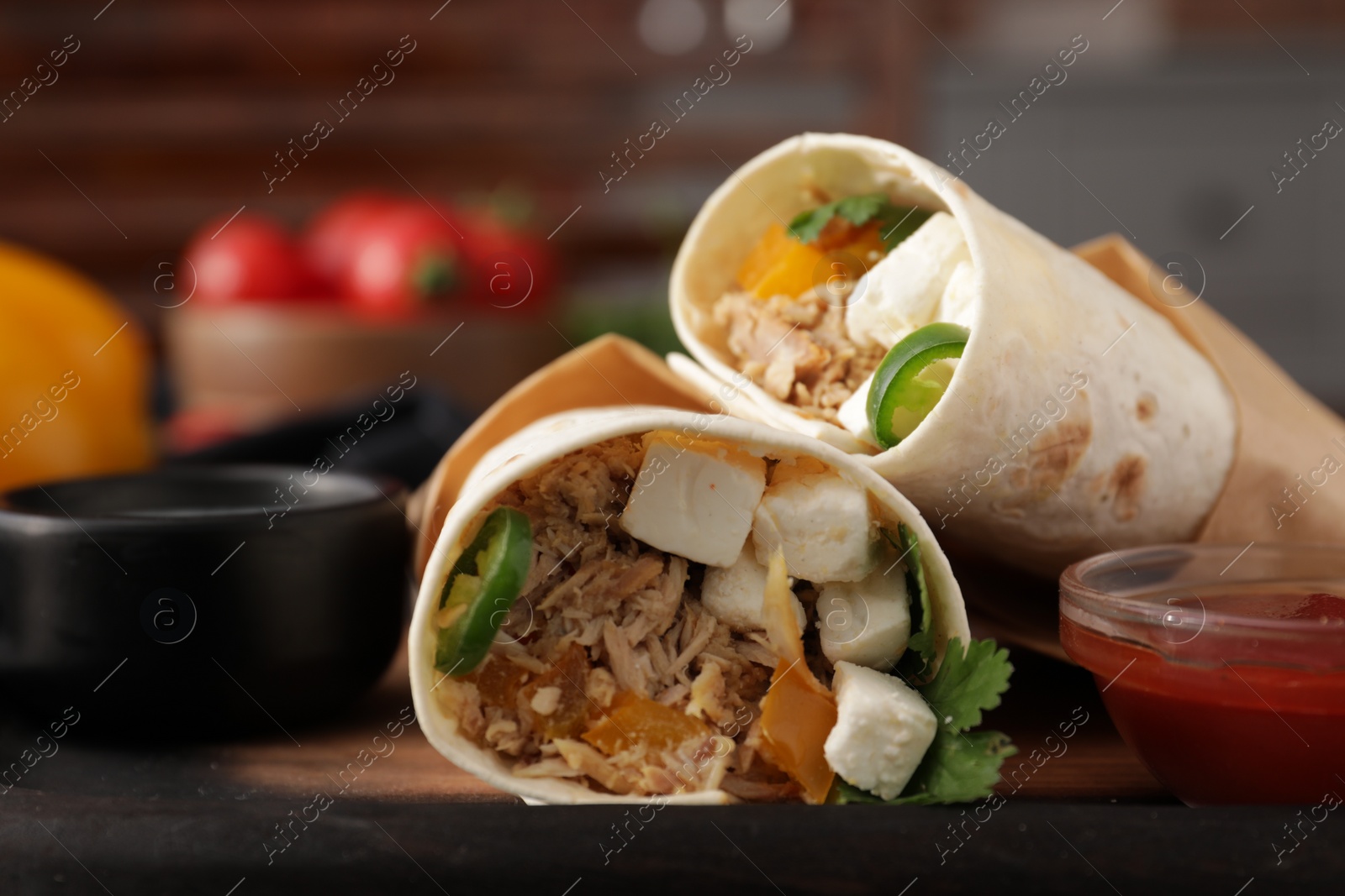 Photo of Delicious tortilla wraps with tuna, cheese, vegetables and sauce on table, closeup