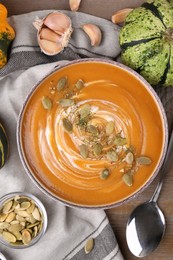 Photo of Flat lay composition with bowl of delicious pumpkin soup on wooden table