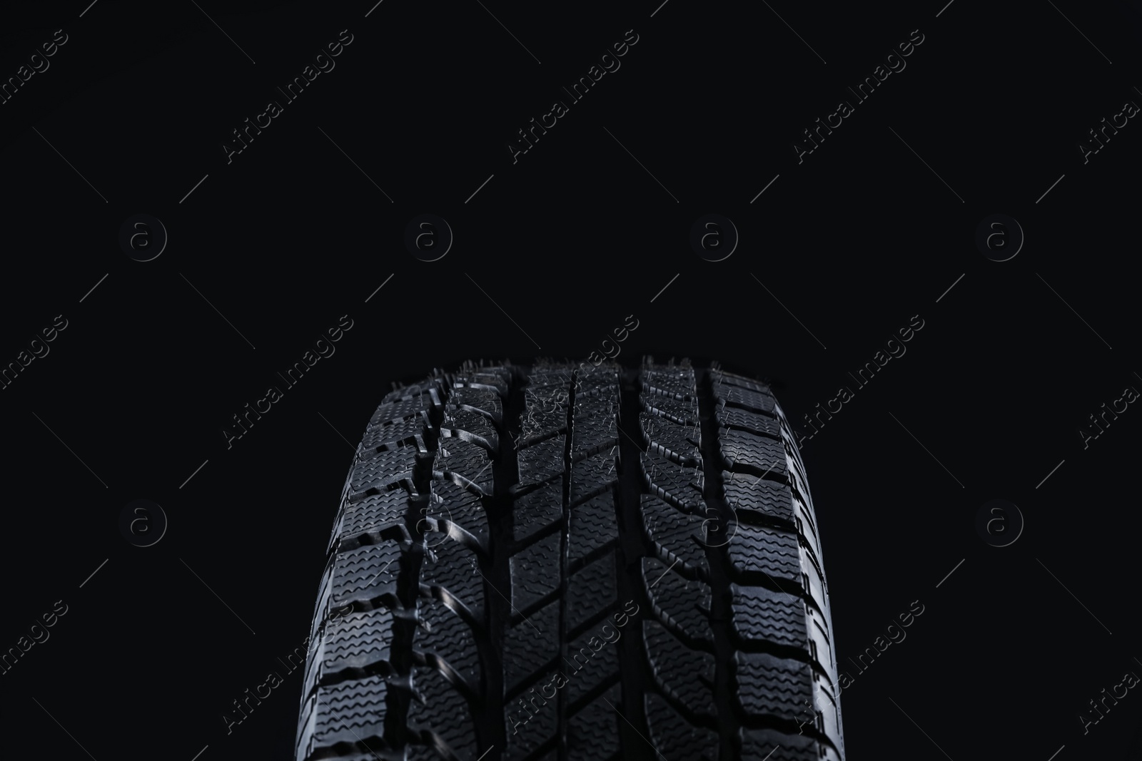 Photo of Winter tire on black background, closeup. Car maintenance