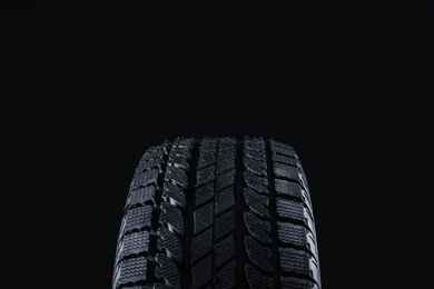 Photo of Winter tire on black background, closeup. Car maintenance
