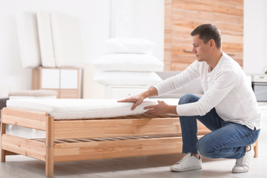 Man touching soft mattress in furniture store