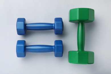 Photo of Colorful vinyl dumbbells on light background, flat lay