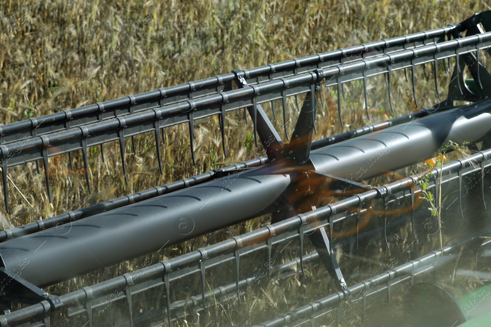 Photo of Modern combine harvester working in agricultural field, closeup view of reel